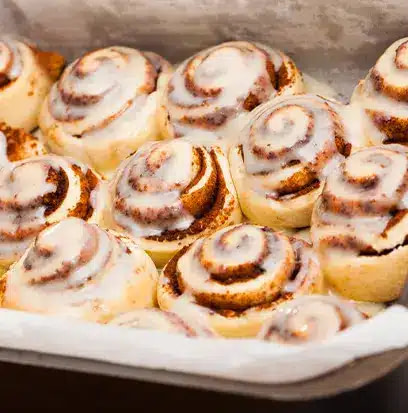 cinnamon buns with icing on a white plate