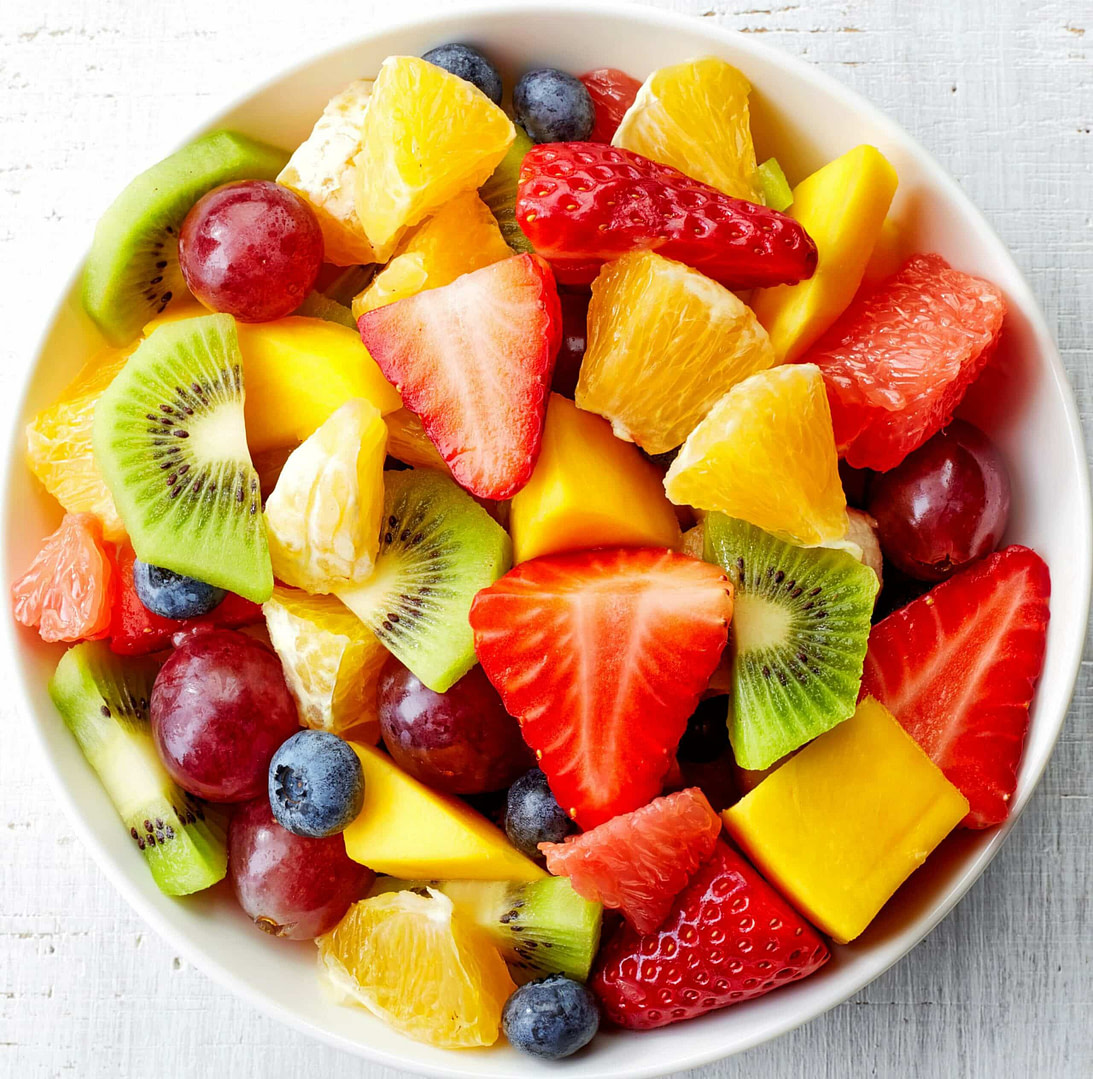 a bowl of mixed fruit on a white table