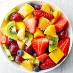 a bowl of mixed fruit on a white table