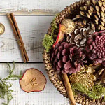 a basket filled with pine cones, apples and cinnamon sticks