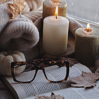 candles, an open book, and autumn leaves on a window sill