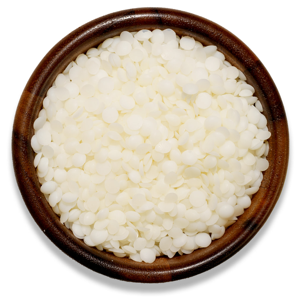 white wax in pellets in a wooden bowl on a white background