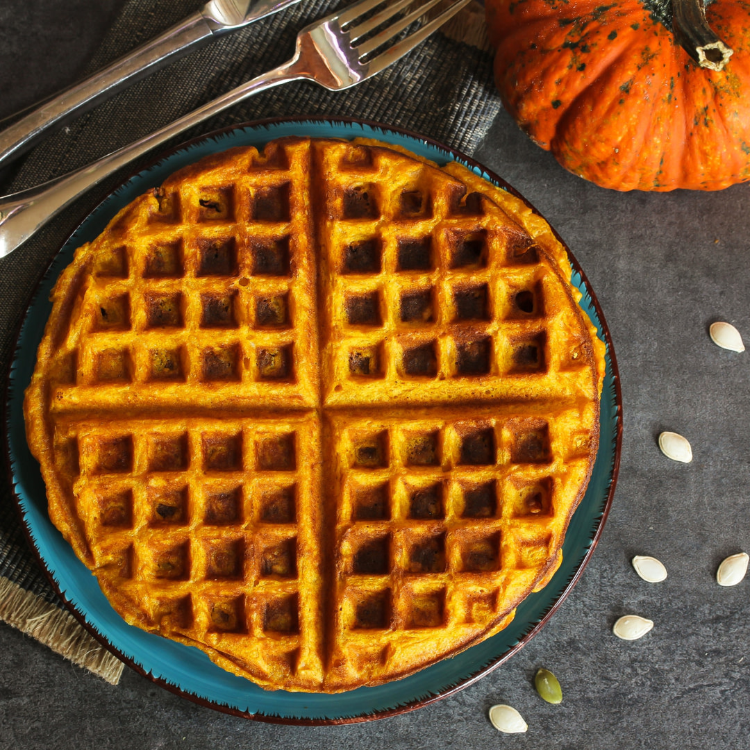 pumpkin waffles on a blue plate with a fork and knife