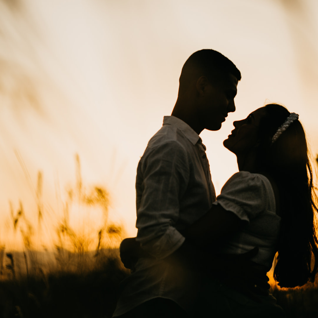 silhouette of a couple embracing in a field at sunset