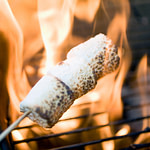 a marshmallow on a stick being cooked on a grill