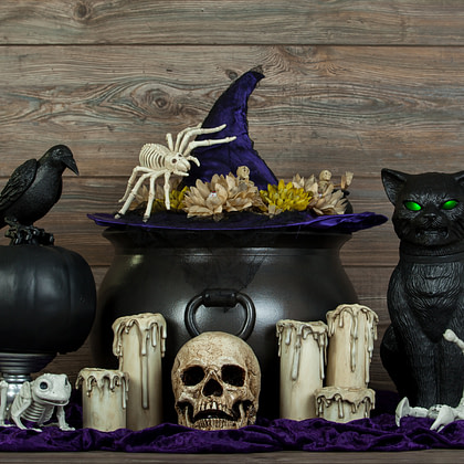 a cat sits on top of a cauldron with other halloween decorations