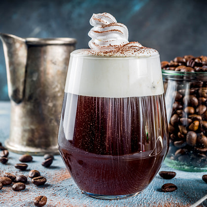 coffee drink in a glass with whipped cream and coffee beans