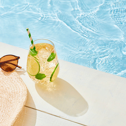 a hat, sunglasses and a drink by the pool