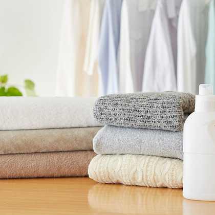 a stack of towels and a bottle of laundry detergent on a wooden table