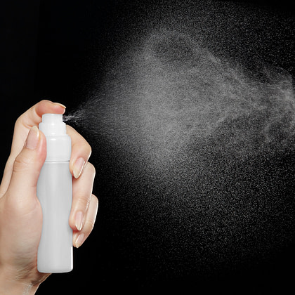 A person holding a spray bottle with white powder coming out of it