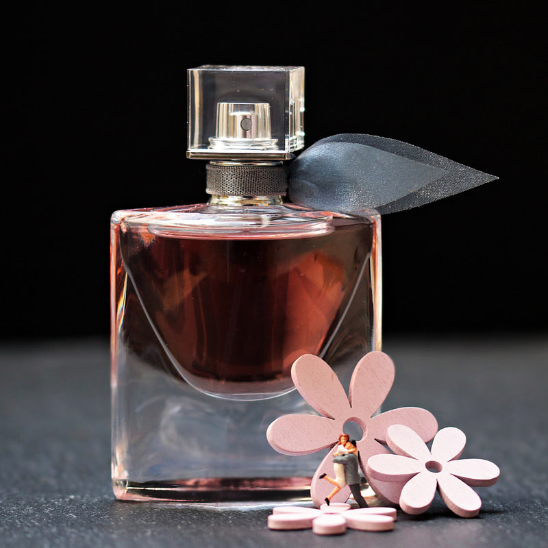 a bottle of perfume with flowers on a black surface