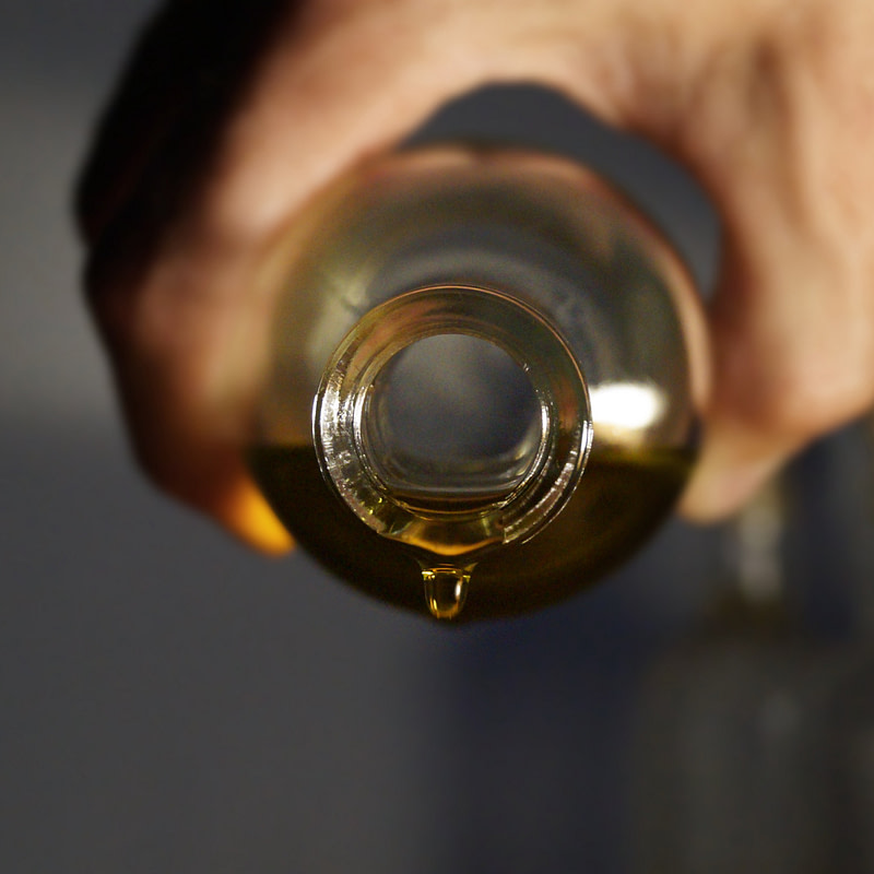 a bottle of olive oil being poured into a glass