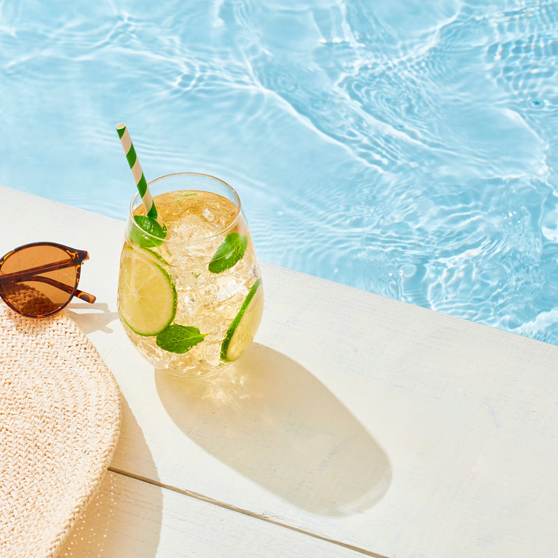 a hat, sunglasses and a drink by the pool
