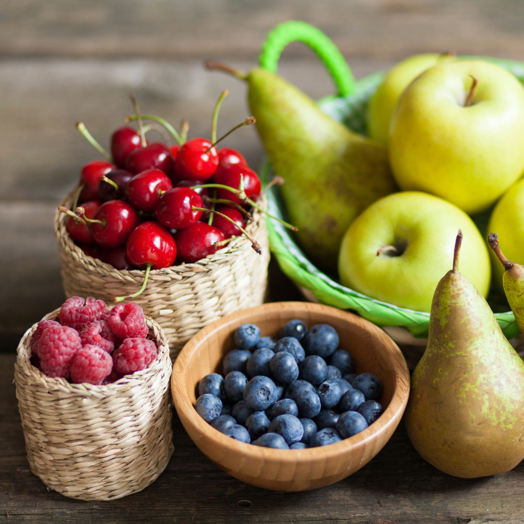 various fruits and berries in baskets on a wooden table