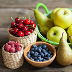 various fruits and berries in baskets on a wooden table