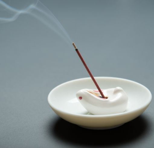 an incense stick in a white bowl with smoke coming out of it