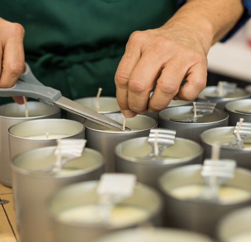 a person is cutting a candle wick with a pair of scissors