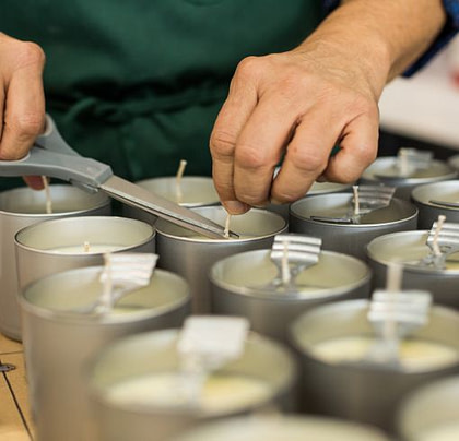man preparing candles and cutting wicks