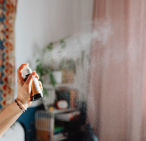 a person holding an air freshener in front of a couch