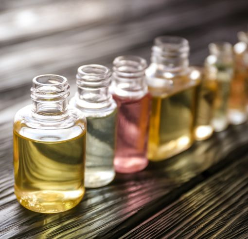 Several bottles of fragrance oils are lined up on a wooden table.