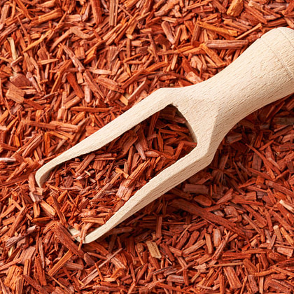 A wooden scoop overflowing with red shavings