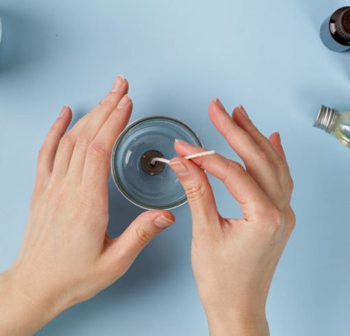 Hands fixing wick in transparent candle jar