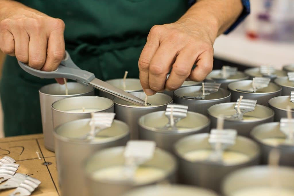 a person is cutting a candle wick with a pair of scissors