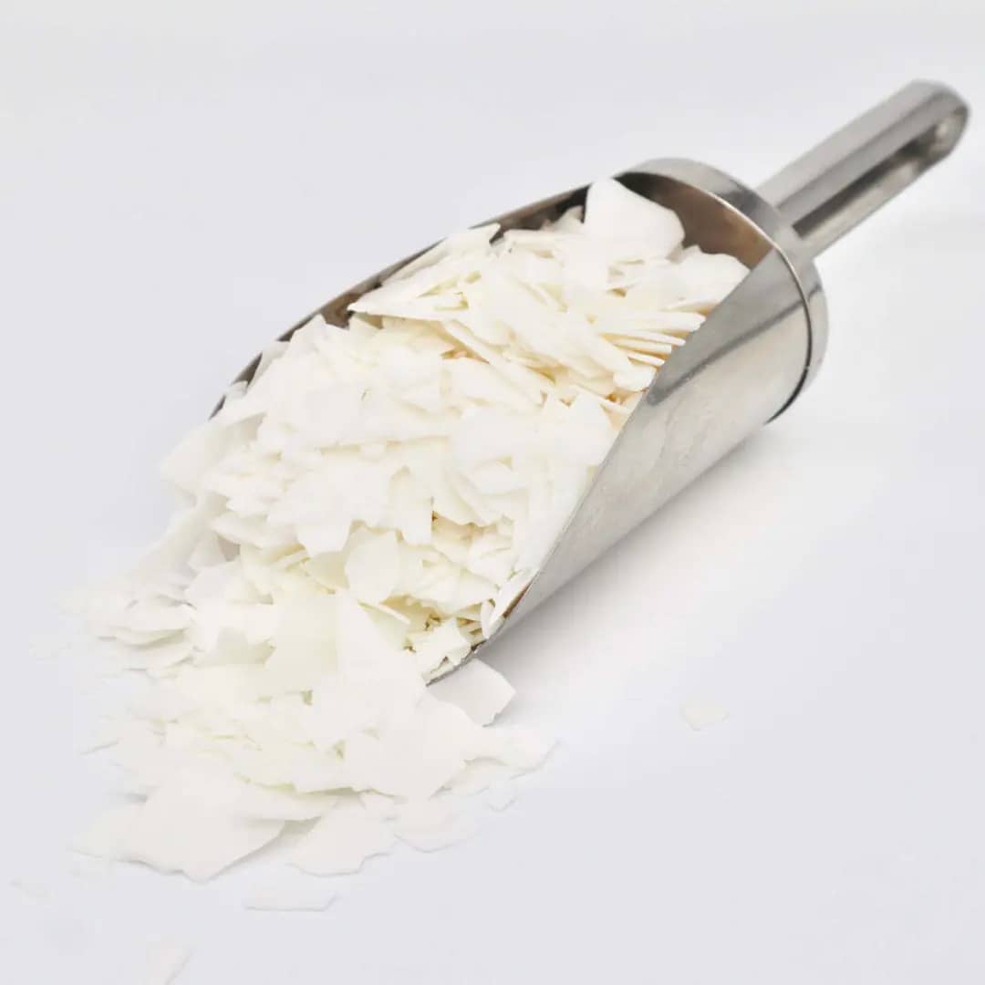 Soy wax flakes in a stainless scoop